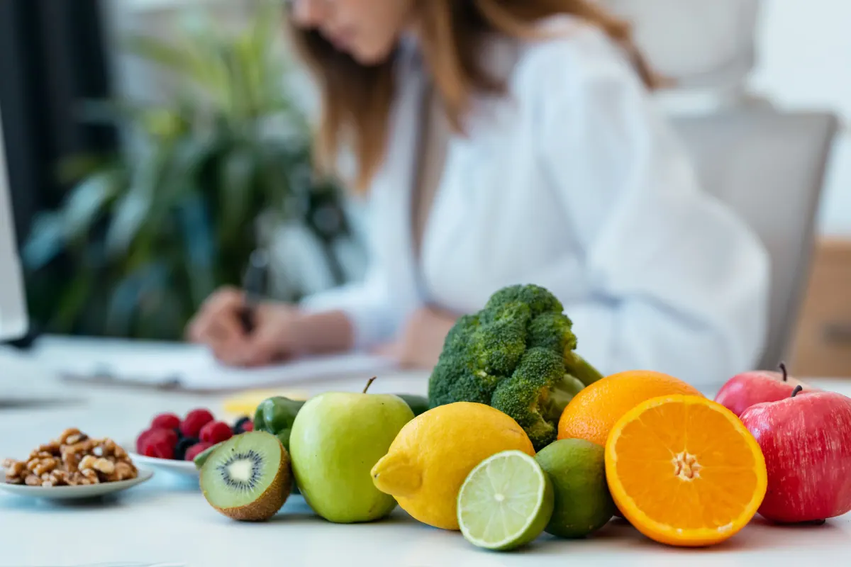 Fresh fruit and vegetables in the foreground while a clinician works in the background